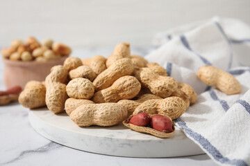 Fresh unpeeled peanuts on white marble table, closeup