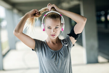 Woman preparing for workout with headphones and tying hair