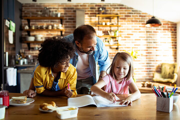 Father helping children with homework at kitchen table