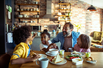 Joyful family breakfast with father and children in home kitchen