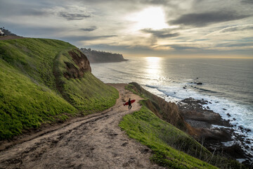 Naklejka premium Surfer's Journey Down the Rugged Bluff Trail