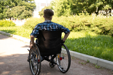 young disabled man in wheelchair walking park and listening music