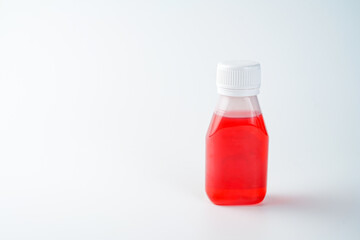 Red cough syrup in plastic bottle isolated on white background