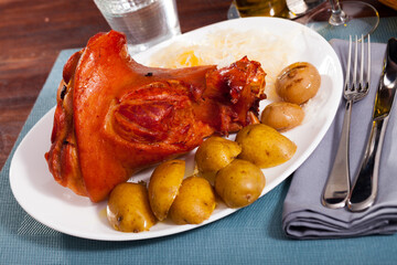 Oven baked pork knuckle with potatoes and cabbage on plate. High quality photo