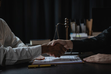 A professional male lawyer in a formal suit shakes hands with a client after making a deal and...