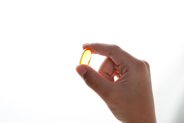 fingers holding a oil filled capsule, soft gel, food supplements, fish oil, omega 3 omega 9