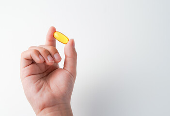 fingers holding a oil filled capsule, soft gel, food supplements, fish oil, omega 3 omega 9