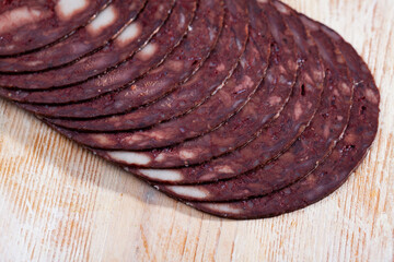 Thin slices of traditional Catalan blood sausage (black botifarra) on wooden background..