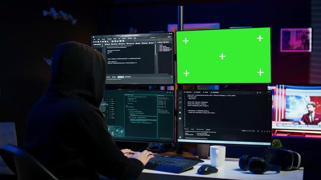 Dangerous man hacking using green screen PC, stealing credit card numbers and infiltrating banking systems. Hacker running code in apartment on mockup computer display, camera B