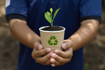environment Earth Day.The boy's hand holding a paper coffee cup with a recycling icon. To plant...