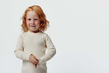 Red haired girl in white sweater standing in front of white background in a fashionable pose