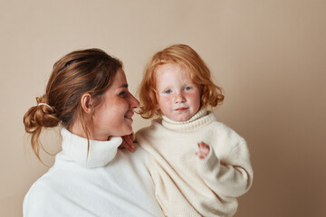 Mother and daughter embracing in white turtleneck sweaters, family love, fashionable and cozy...