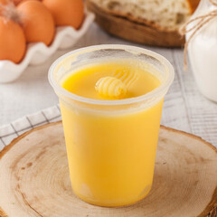Melted butter in a plastic cup made from farm milk. Dairy products