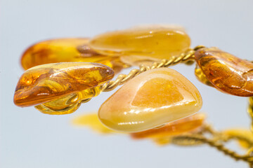 Vibrant yellow and orange polished amber crystal and copper wire tree on a blue chalcedony mineral base macro isolated on white surface