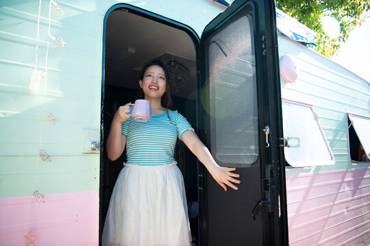 キャンピングトレーラーのドアを開けて笑っている女性