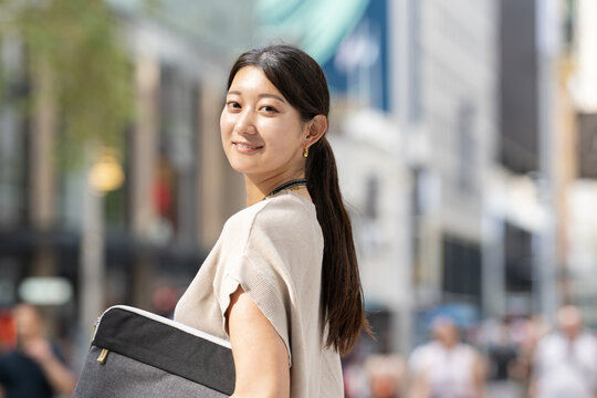 街でパソコンケースを抱えてこちらを見ている女性