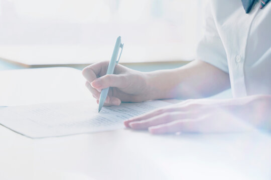紙に筆記する女子学生の手元