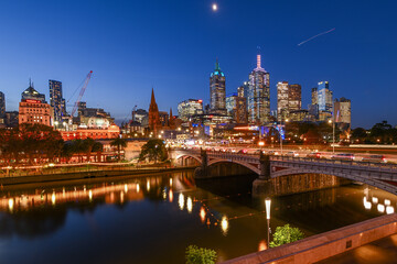 Flinders Street Station and the Melbourne City skyline behind the Yarra River during sunset in Melbourne