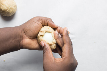 Egg being wrapped in dough to make nigerian egg roll, process of making nigerian egg roll and small...