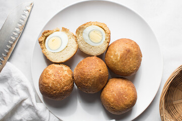 Overhead view of homemade nigerian egg roll, freshly made african egg roll on a white plate, flatlay of egg wrapped in fried dough