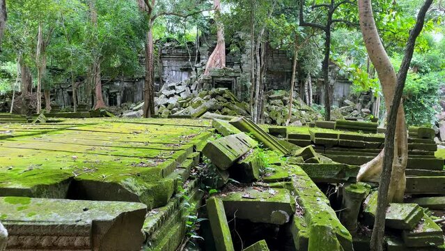 Tilt up establishing of the mossy ruins of the Prasat Beng Mealea temple in Cambodia on a sunny day, tourist site in the middle of the forest.