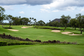 Beautiful scenic golf course from tee box to green, lava rocks, sand traps and palm trees, tropical...