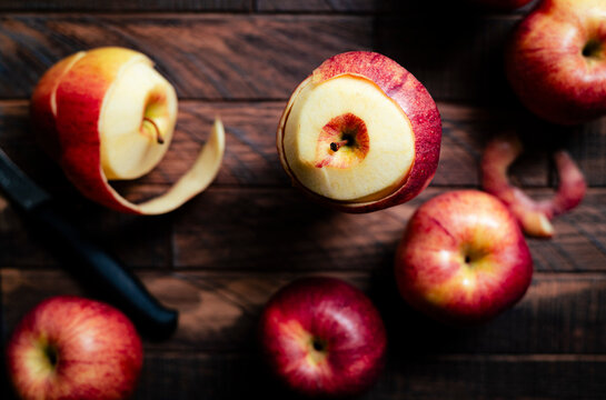 peeling red apples on a wooden surface