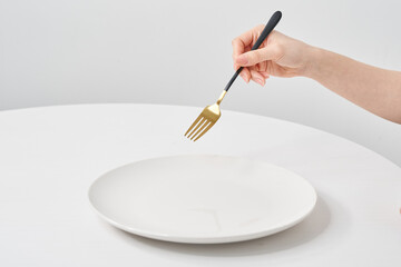 白いお皿と、フォークを持つ女性の手元