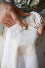  women holding white color dirty shirt, showing making stain