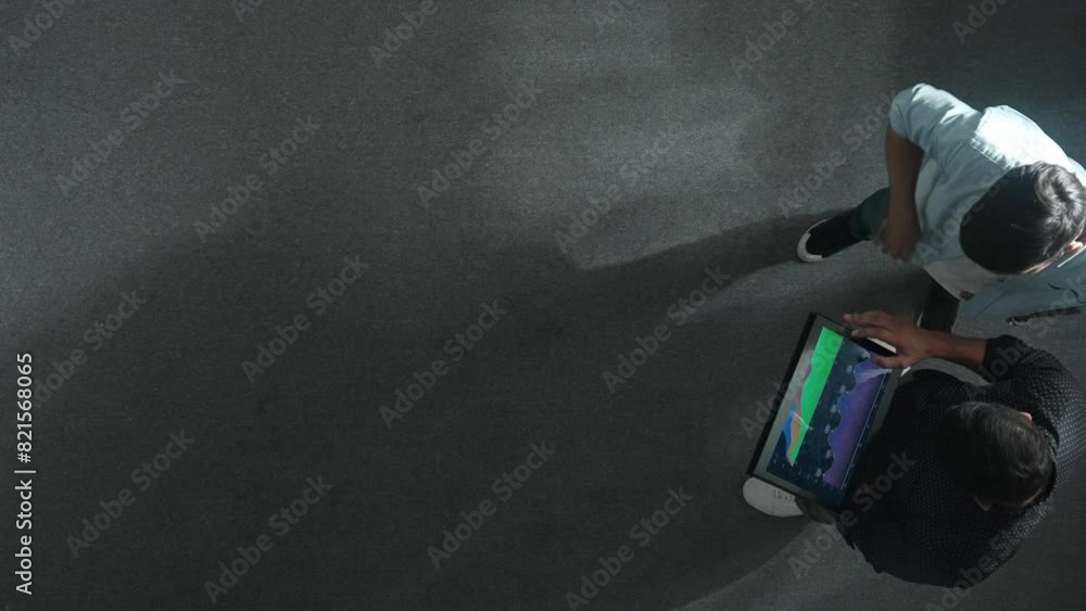 Poster top down view of manager stand with investor while holding tablet and looking at financial statistic