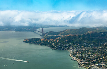 Aerial view of clouds rolling over the Marin Headlands, Golden Gate Bridge, and the marinas of Sausalito.