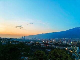Atardecer con vista a la ciudad de Caracas en Venezuela. Cielo azul, poca nubosidad y horizonte color naranja.