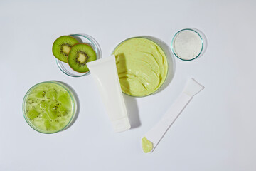 Several round shape glassware containing kiwi and exfoliating cream in white and yellow color,...