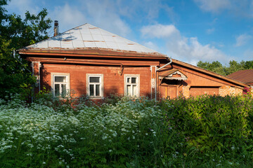 Russian traditional wooden house decorated with house carvings and a front garden on a sunny summer...