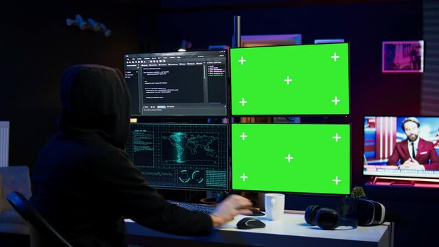 Hooded man writing lines of code on green screen PC from apartment, trying to get past security systems. Evil hacker using mockup computer to make scripts that can hack devices, camera B