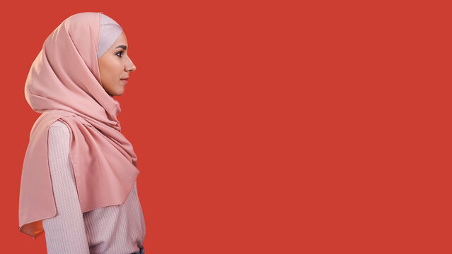 Muslim woman. Islamic beauty. Profile of confident religious girl in casual hijab headscarf isolated on red empty space advertising background.