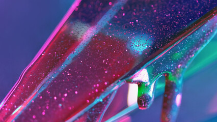 Sparkling liquid. Glowing fluid. Pink shiny gel bubbles flowing down on oil glass texture on blue green defocused abstract background empty space.