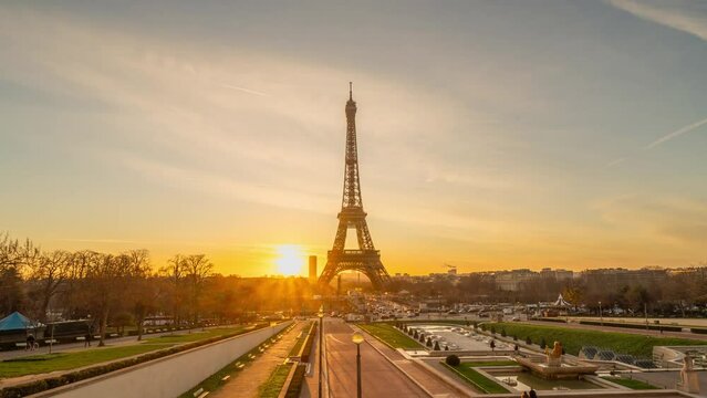 4K timelapse of Paris at sunrise with the Eiffel Tower at the Trocadero gardens and the traffic,the most famous landmark in Paris,France.Golden hour in a cloudy sunny day
