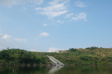 a portrait of a reservoir in a village with calm water and green scenery 