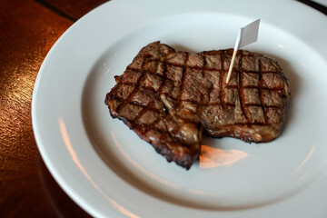 Grilled striploin steak served on white plate. Embroidered the white flag. Main course dish in Argentina steakhouse restaurant.