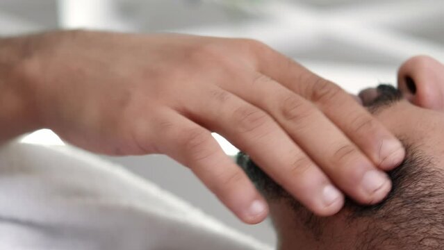 Vertical video. Beard care. Facial treatment. Cosmetic product. Confident satisfied man applying face skin shea butter oil with dropper on stubble after shower.