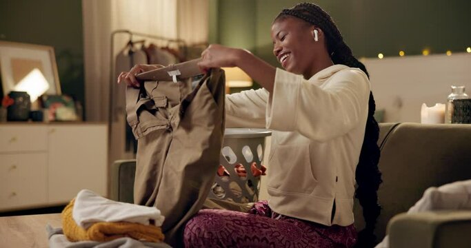 Home, laundry and woman listening to music, relax and fold clean clothes in basket. Cleaning, fabric and streaming radio, sound or enjoy audio online with technology and calm night in apartment