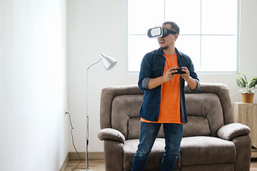 Excited man playing virtual games using VR glasses and joystick at home
