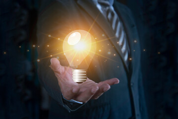 Businessman hand holding virtual light bulb icon. Concept of motivation for success and thinking of...