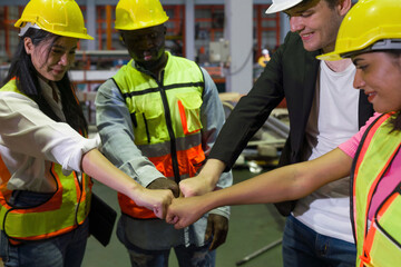 Group of construction workers clad in hard hats and reflective vests, are locked in a cordial fist...
