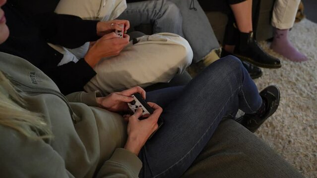 Group of friends sat on couch playing on games console. Over Shoulder.