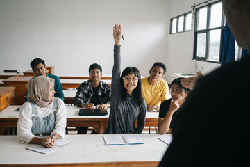 Asian Female Student Raising Hand To Ask Questions During A Class At School