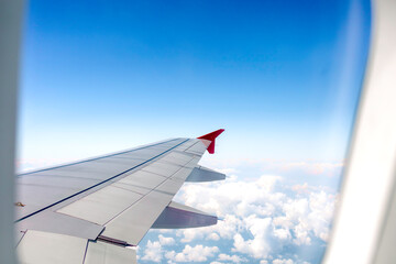 Clear blue sky with fluffy ornamental cumulus clouds, panoramic view from an airplane, wing close-up.