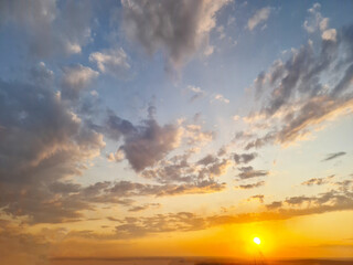 The sky was filled with an array of clouds during the sunset, creating a breathtaking natural landscape with hues of amber and red. The afterglow of sunlight painted the atmosphere beautifully.