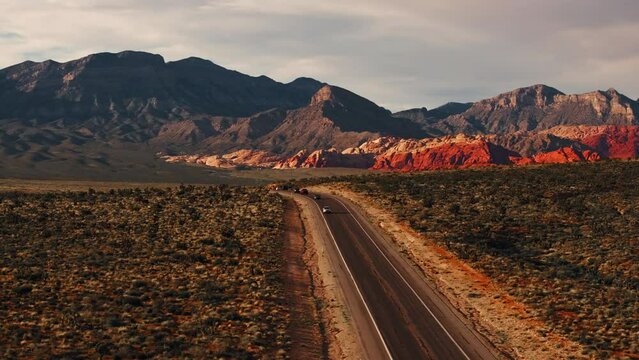 Aerial view of traffic on a highway with Red Rock Canyon national park in the background during sunset
